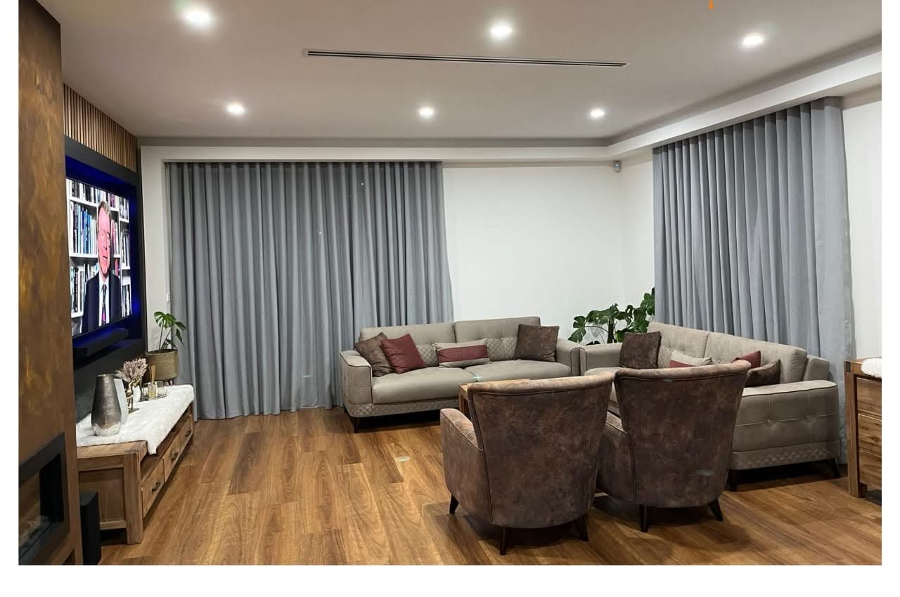 Grey sheer and blockout curtains in a media lounge